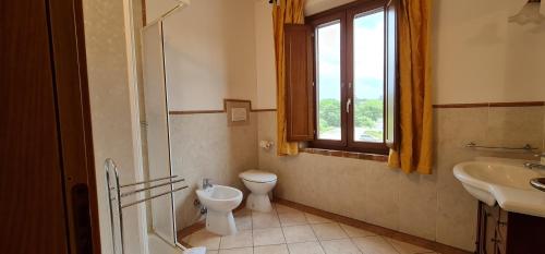 a bathroom with a toilet and a sink and a window at Oasi Del Grillo in Castelnuovo Berardenga