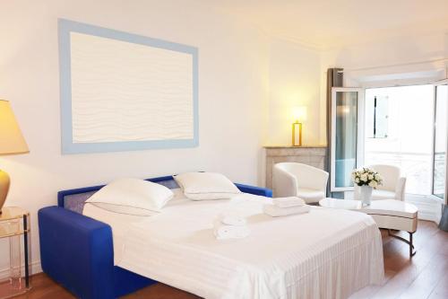 - une chambre blanche avec un lit bleu et deux chaises dans l'établissement 2-Br City center near Croisette & Palais, à Cannes