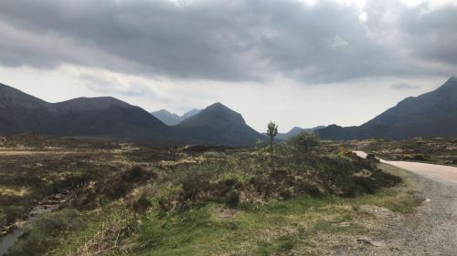 a road in a field with mountains in the background at Pooltiel View in Milovaig