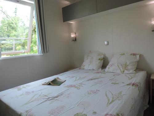 um quarto com uma cama com colcha floral e uma janela em MUNSTER camping de la FECHT em Munster