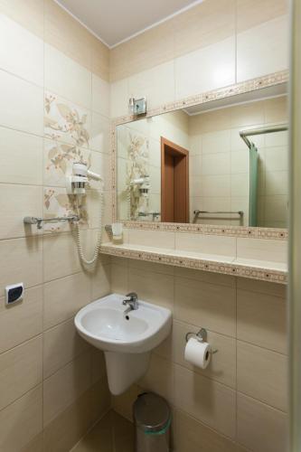 a bathroom with a sink and a mirror at Angela Domki i Pokoje in Pobierowo