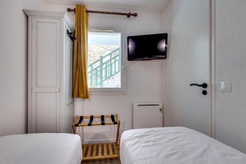 Cette chambre comprend deux lits, une fenêtre et une télévision. dans l'établissement Le Zeste, à Soustons