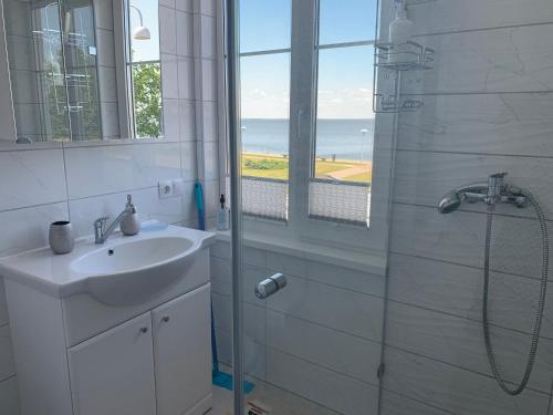 ein Bad mit einem Waschbecken und einer Dusche mit einem Fenster in der Unterkunft Butas Prie Marių in Juodkrantė