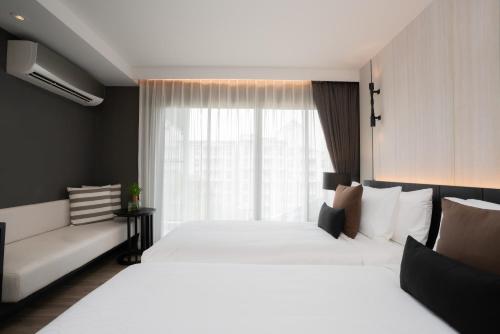 a hotel room with two beds and a window at Bayphere Hotel Pattaya JC in Na Jomtien
