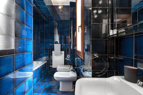 a blue tiled bathroom with a toilet and a sink at Ca’ Pesaro rooftop terrace apartment. in Venice