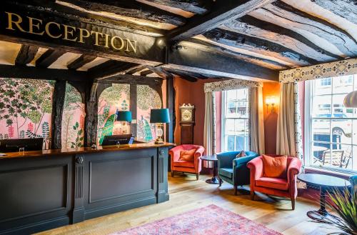 een kamer met stoelen en een bar met een bord dat de receptie leest bij The George Hotel in Colchester