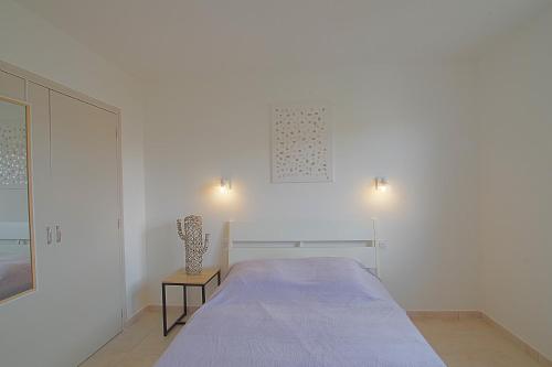 ein weißes Schlafzimmer mit einem Bett und einem Beistelltisch in der Unterkunft Casa Flamingo - Appartement calme et moderne - 5 - in Canet-en-Roussillon