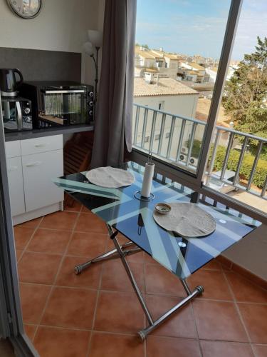 - une table en verre dans la cuisine avec balcon dans l'établissement Studio plage du môle, au Cap d'Agde