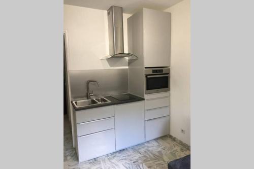 une cuisine avec des armoires blanches et un évier dans l'établissement Studio meublé proche plages et vieille ville, à Antibes