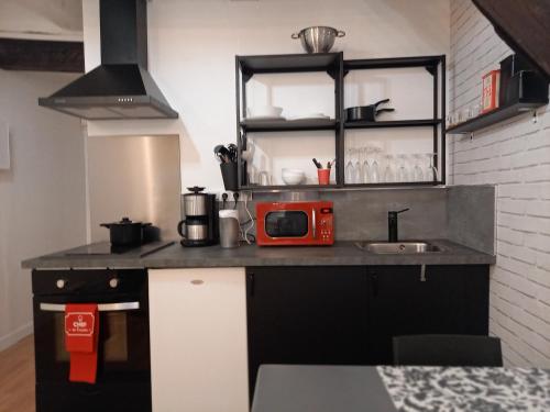 une petite cuisine avec un four micro-ondes rouge sur un comptoir dans l'établissement Charmant studio dans le Vieux Tours, à Tours