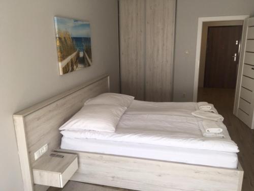 a bedroom with a bed with a wooden frame at Apartament Silence Baltic Skandynawski in Pobierowo