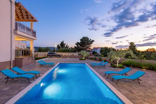 a swimming pool with chairs and a house at Villa Grandioza in Seline