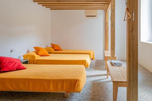 three beds in a room with orange sheets at Agriturismo La Derta in Bellagio