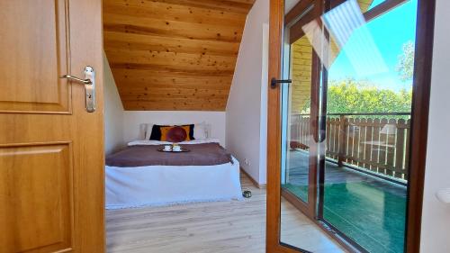 a door leading to a bedroom with a bed on a balcony at Domek Letni Ryn in Ryn