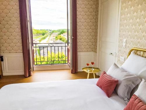 a bedroom with a bed and a large window at La Promenade - Appartement de charme avec vue sur le canal et ses écluses - Centre historique in Redon