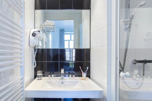 a white bathroom with a sink and a mirror at Le Grand Hotel de Plombières by Popinns in Plombières-les-Bains
