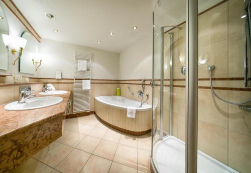 a bathroom with two sinks and a shower and a tub at Ringhotel Mönch`s Waldhotel in Unterreichenbach
