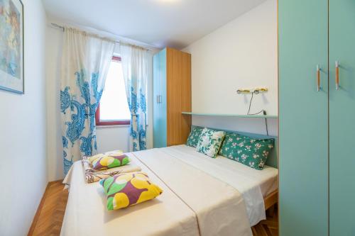 een kleine slaapkamer met een bed met kleurrijke kussens bij Lily in Baška