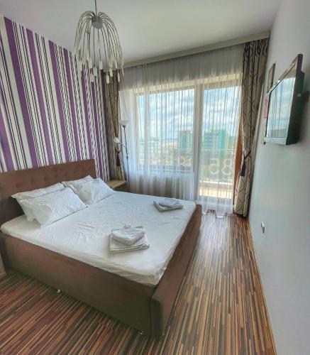 a bedroom with a bed and a large window at Sunset Sea View Apartament in Mamaia