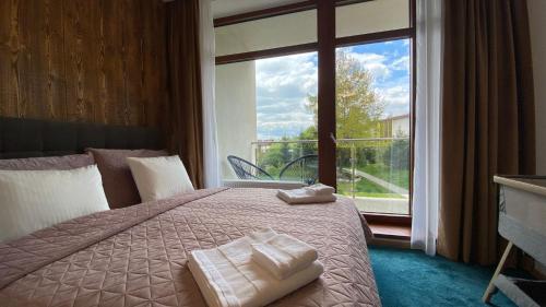 a bedroom with a bed and a large window at Apartmán C110 v Hrebienok Resort II in Vysoke Tatry - Stary Smokovec
