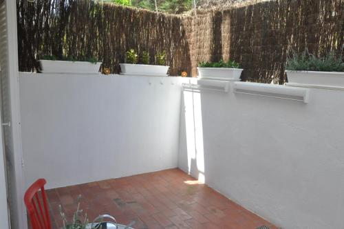 Una valla blanca con tres plantas en macetas. en La Yeye Offre d'automne de 6 nuits & 6 Nights Autumn Offer, en Port de la Selva