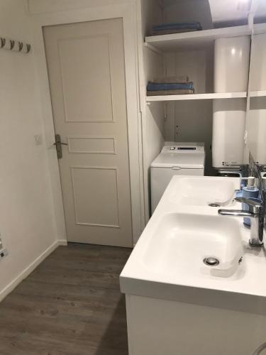 La salle de bains blanche est pourvue d'un lavabo et d'une porte blanche. dans l'établissement LE MONTAIGNE - Wifi fibre- Coeur du centre ville-PROPERTY RENTAL NM, à Périgueux