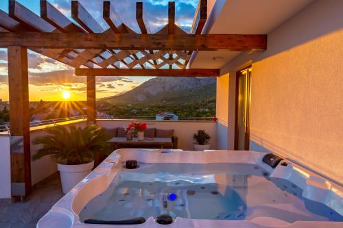 a hot tub on a balcony with a view of the sunset at Villa Grandioza in Seline