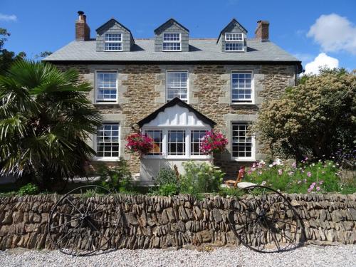 a large stone house with a stone fence in front of it at Pengelly Farmhouse B&B in Truro