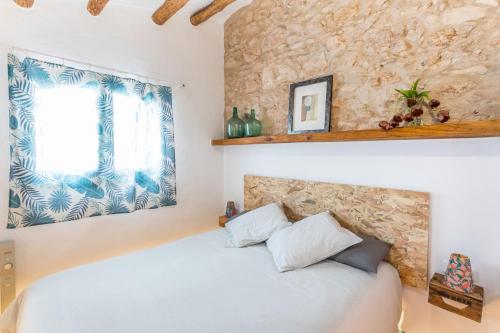 Un dormitorio con una cama y una pared de piedra. en Apartamento rústico reformado con encanto (Garraf), en Sant Pere de Ribes