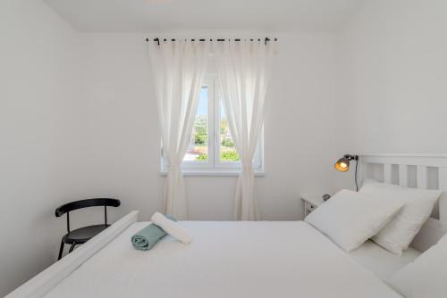 ein weißes Schlafzimmer mit einem weißen Bett und einem Fenster in der Unterkunft New and chic place near Old Town of Trogir in Trogir