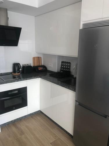 a kitchen with white cabinets and a black refrigerator at La Rosa Apartment Los Boliches Fuengirola Malaga Spain in Fuengirola