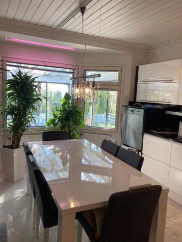 a kitchen with a white table and chairs and windows at Vanha omakotitalo, 3km Olavinlinnaan in Savonlinna