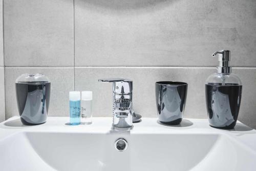a bathroom sink with two faucets and two cups and a bottle at Triana modern & luxury in Seville