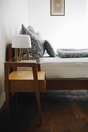 a bed with a nightstand and a table with a lamp at Heurigenhof Bründlmayer in Langenlois
