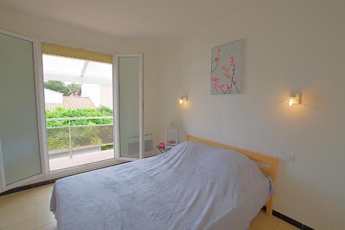 a bedroom with a bed and a large window at Casa Flamingo - Appartement charmant et moderne - 6 - in Canet-en-Roussillon