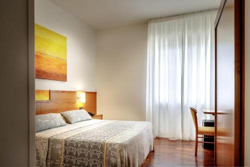 a bedroom with a bed and a desk and a window at Euro Hotel in Nuoro
