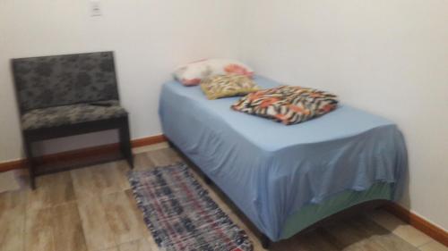 a small bed and a chair in a room at Pousada Família Limas in Joinville