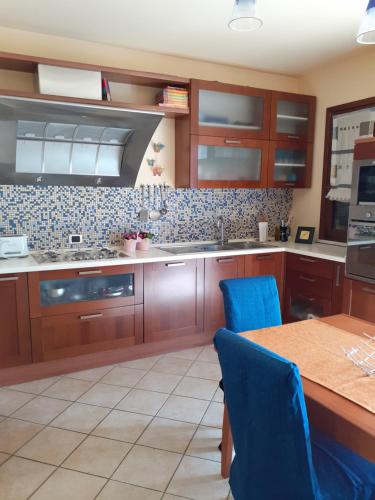 uma cozinha com armários de madeira e uma mesa com cadeiras azuis em A casa di Sabina, appartamento a Castelbuono em Castelbuono