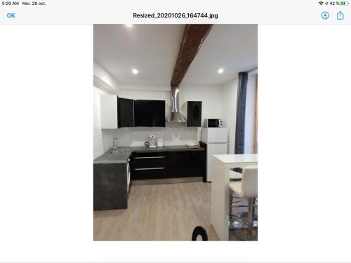 une cuisine avec des armoires en noir et blanc et une table dans l'établissement Appartement Plein centre, à Narbonne