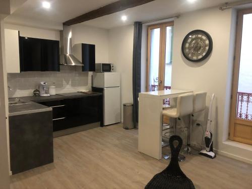 une cuisine avec des appareils en noir et blanc et une table dans l'établissement Appartement Plein centre, à Narbonne