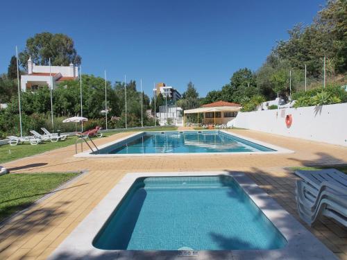 a swimming pool in a yard with chairs and an umbrella at Casa Nikolina in Albufeira