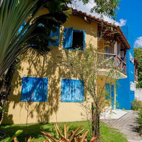 a blue and yellow house with blue windows at Pousada Varanda do Sol in Arraial d'Ajuda