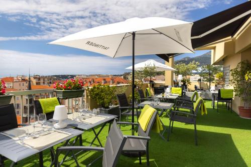 a patio with tables and chairs and an umbrella at Best Western Hotel Mediterranee Menton in Menton