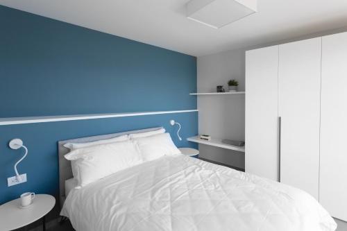 1 dormitorio con cama blanca y pared azul en Ilfico en Cannero Riviera