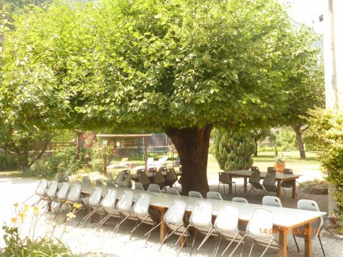 a table and chairs under a tree in a park at La Marmotte De La Meije in Le Bourg-dʼOisans