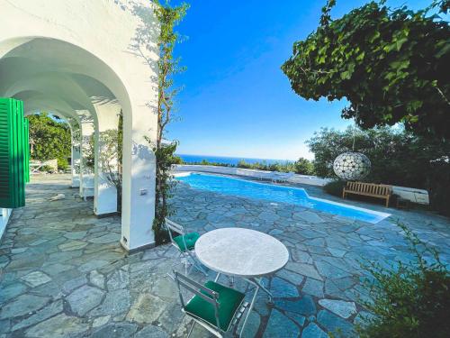 a patio with a table and chairs next to a pool at Il Carrubo Capri in Anacapri