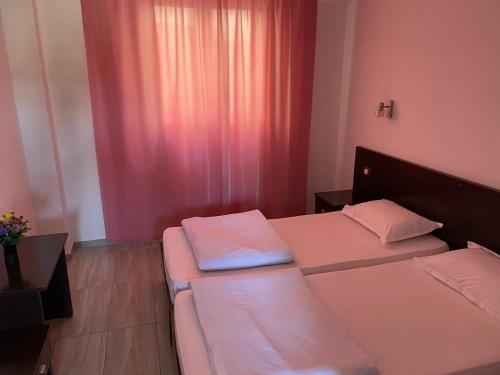 um pequeno quarto com 2 camas e cortinas cor-de-rosa em Vila II Poieniţa em Costinesti