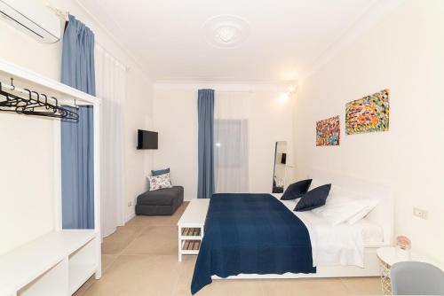 a white bedroom with a bed and a couch at Suite Caronda in Catania