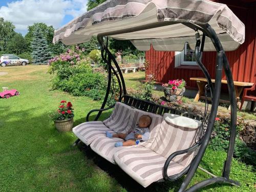 a baby laying on a swing in a yard at Namelis nr 1 Adelės sodyba in Sturmai