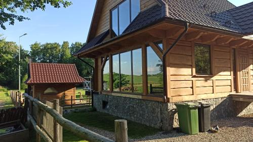 a wooden cabin with glass windows and a fence at Dom Królewski Róg in Giżycko